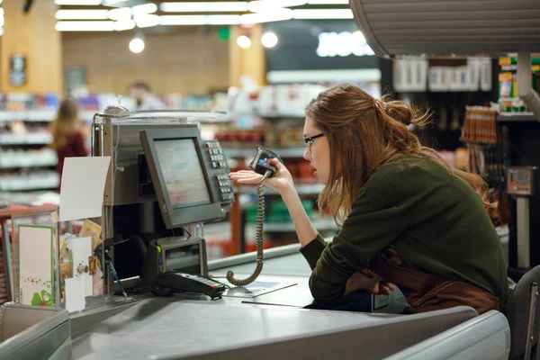 Verwirrte Kassiererin am Arbeitsplatz im Supermarkt. — Stockfoto
