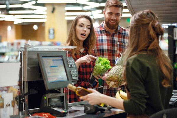 Concentrated young couple standing near cashier's desk.