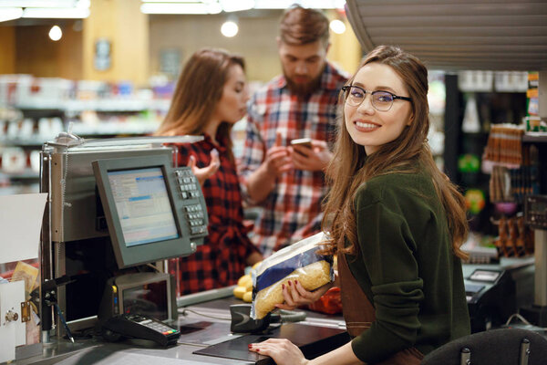 Cashier woman on workspace in supermarket shop.