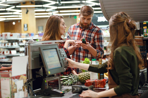 Concentrated young couple standing in supermarket