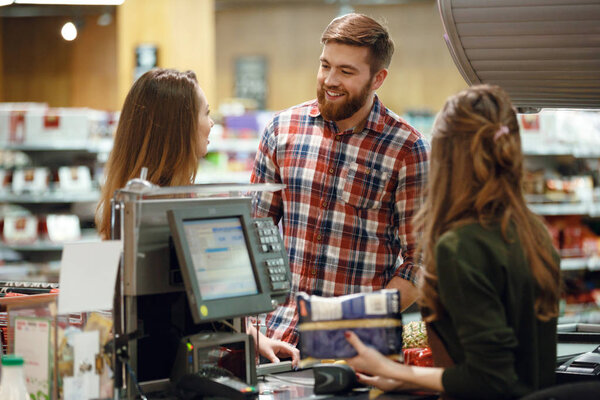 Happy young loving couple standing near cashier's desk