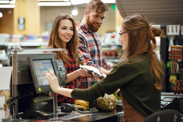 Happy young loving couple standing in supermarket — Stock Photo, Image