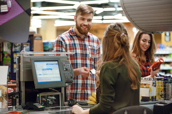Cheerful young man standing in supermarket shop