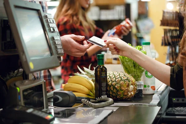Cropped picture of young man gives credit card to cashier — Stock Photo, Image