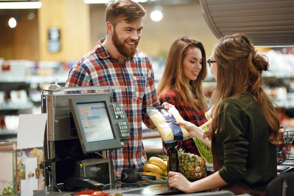 ?heerful young man standing in supermarket shop