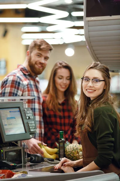 Vrolijke kassa vrouw op werkruimte in supermarkt — Stockfoto