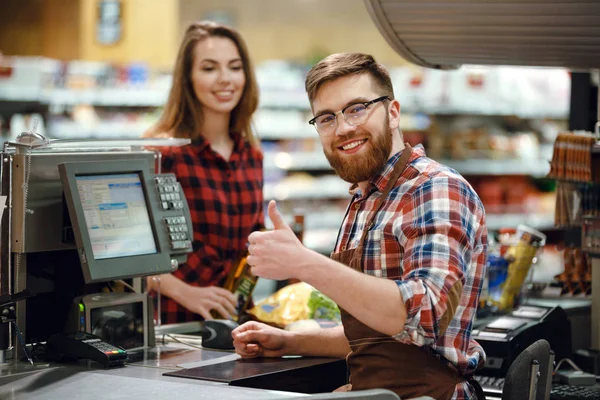 Happy cashier man on workspace in supermarket — Stock Photo, Image