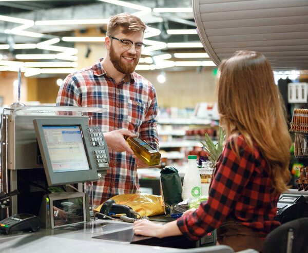 Happy young man standing near cashier's desk in supermarket
