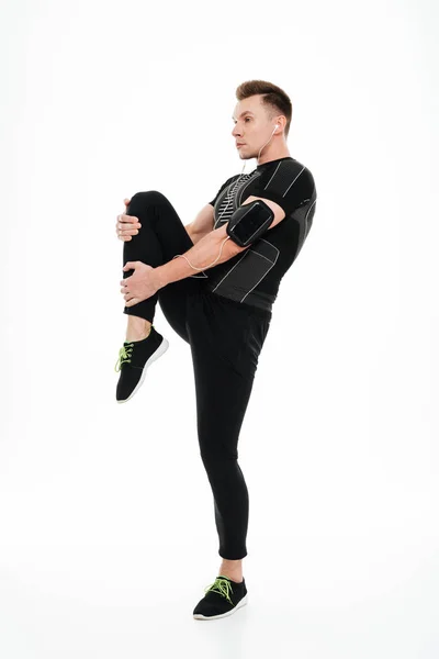 Full längd porträtt av en ung frisk sportsman stretching benen — Stockfoto