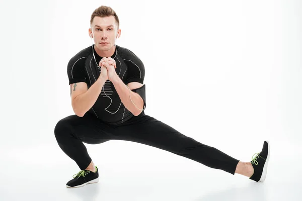 Retrato de un deportista guapo haciendo ejercicios de estiramiento antes de trotar — Foto de Stock