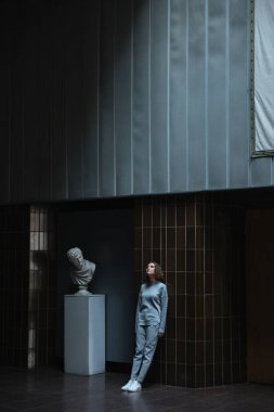 Kadın bir Sanat Galerisi içinde karanlık bir duvara yaslanmış