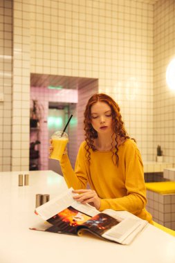 Kafede oturan genç redhead kıvırcık Bayan konsantre