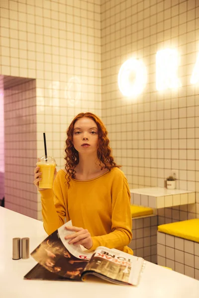 Serious young redhead curly lady sitting in cafe — Stock Photo, Image