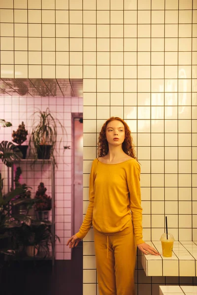 Serious young redhead curly lady standing in cafe — Stock Photo, Image