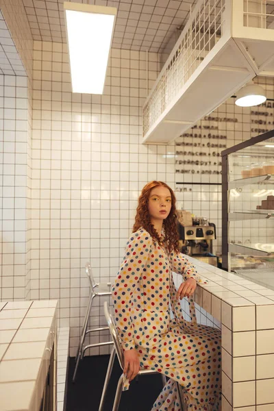 Serious young redhead curly lady sitting in cafe. — Stock Photo, Image