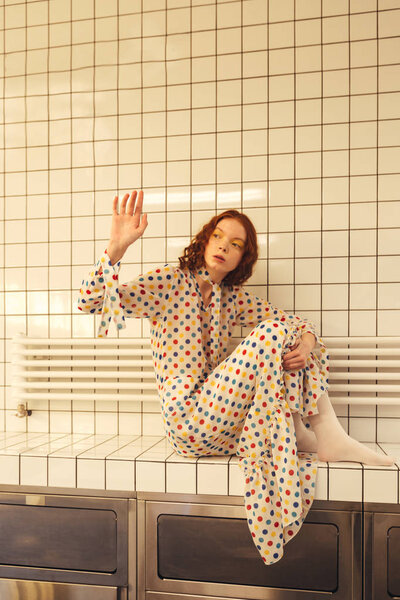 Concentrated young redhead curly woman sitting in cafe