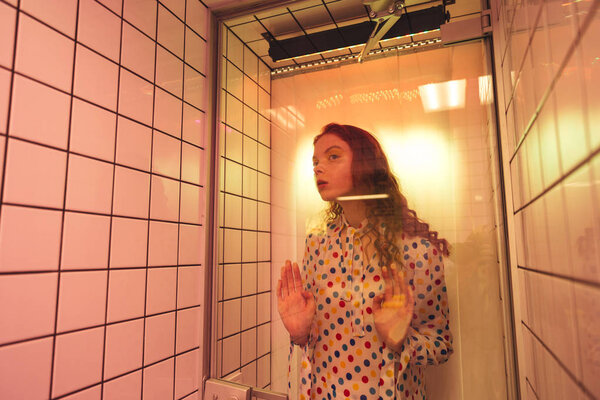 Young redhead curly woman standing in cafe at latrine