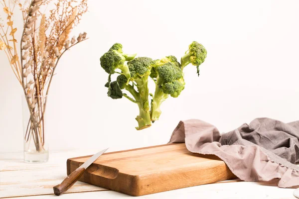 Broccoli interi affettati che volano sopra un tagliere di legno — Foto Stock