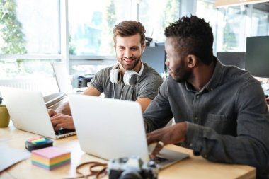 Dizüstü bilgisayar kullanarak office coworking içinde oturan genç meslektaşları gülümseyen