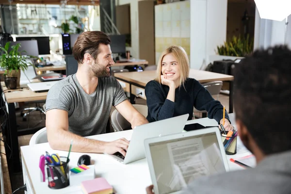 Heureux jeunes collègues assis dans le bureau coworking — Photo