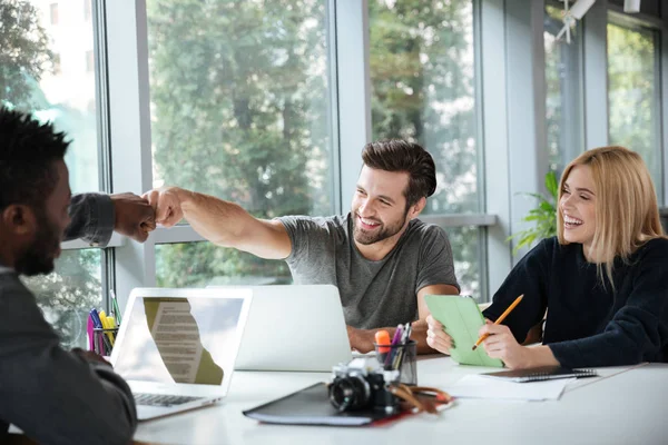 Sorridente giovani colleghi seduti in ufficio coworking — Foto Stock