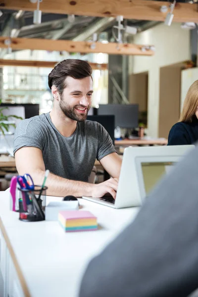 Joyeux jeune homme assis dans le bureau coworking — Photo