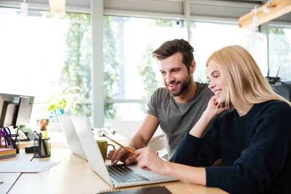 Joyeux jeunes collègues assis dans le bureau coworking à l'aide d'un ordinateur portable — Photo