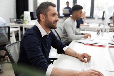 Oturma ve onun bilgisayar çalışan genç bir erkek işçi