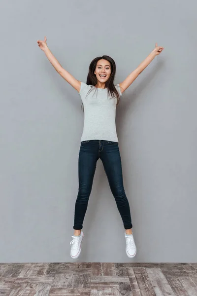 Mujer joven feliz con las manos levantadas saltando en el aire — Foto de Stock