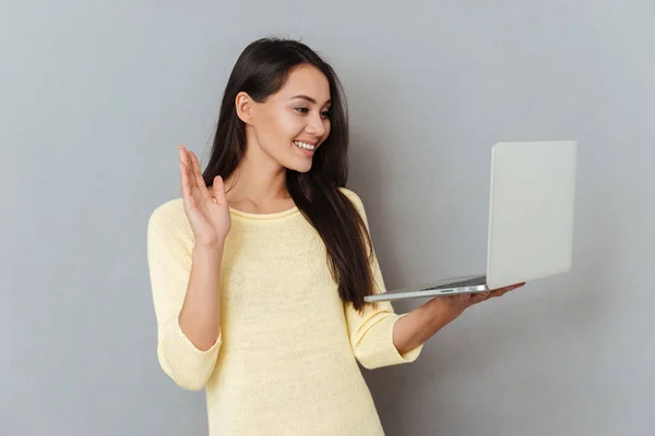 Joyeux charmant jeune femme tenant un ordinateur portable et ayant une vidéoconférence — Photo