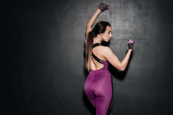 Achteraanzicht van een gezonde vrouw in sportkleding bedrijf halters — Stockfoto