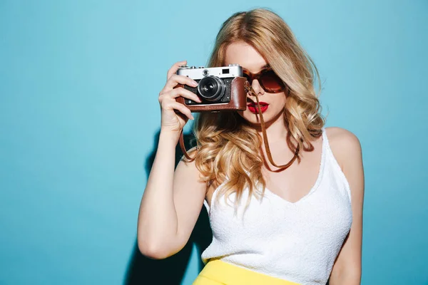 Giovane donna bionda in occhiali da sole scattare foto sulla macchina fotografica retrò — Foto Stock