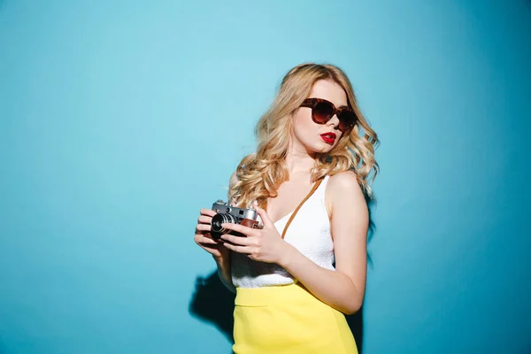 Giovane donna bionda elegante in occhiali da sole con fotocamera retrò — Foto Stock
