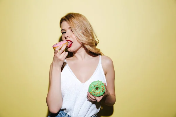 Ung kvinna med ljusa läppar makeup äta donuts. — Stockfoto