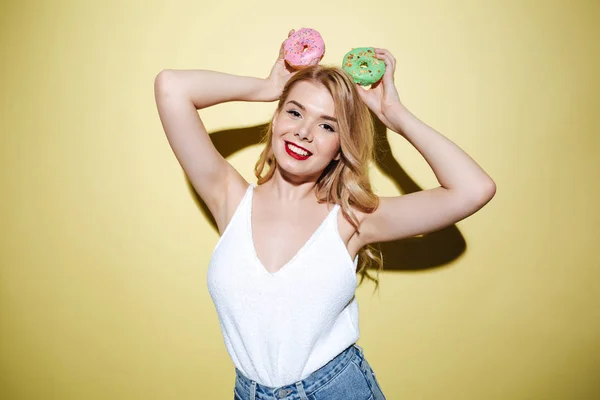 Jovem mulher bonita com lábios brilhantes maquiagem segurando donuts . — Fotografia de Stock