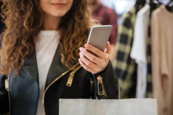 Beskuren bild av glada damen med shoppingkassar som håller telefonen. — Stockfoto