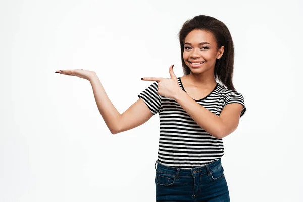 Jovem senhora africana feliz segurando copyspace na mão enquanto aponta — Fotografia de Stock