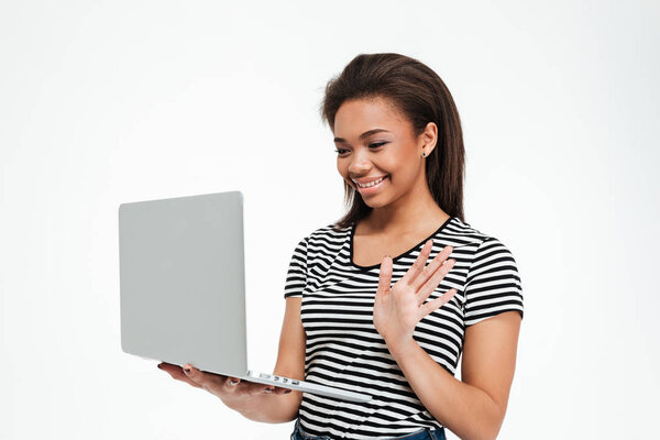 Young smiling afro american woman waving hand to laptop