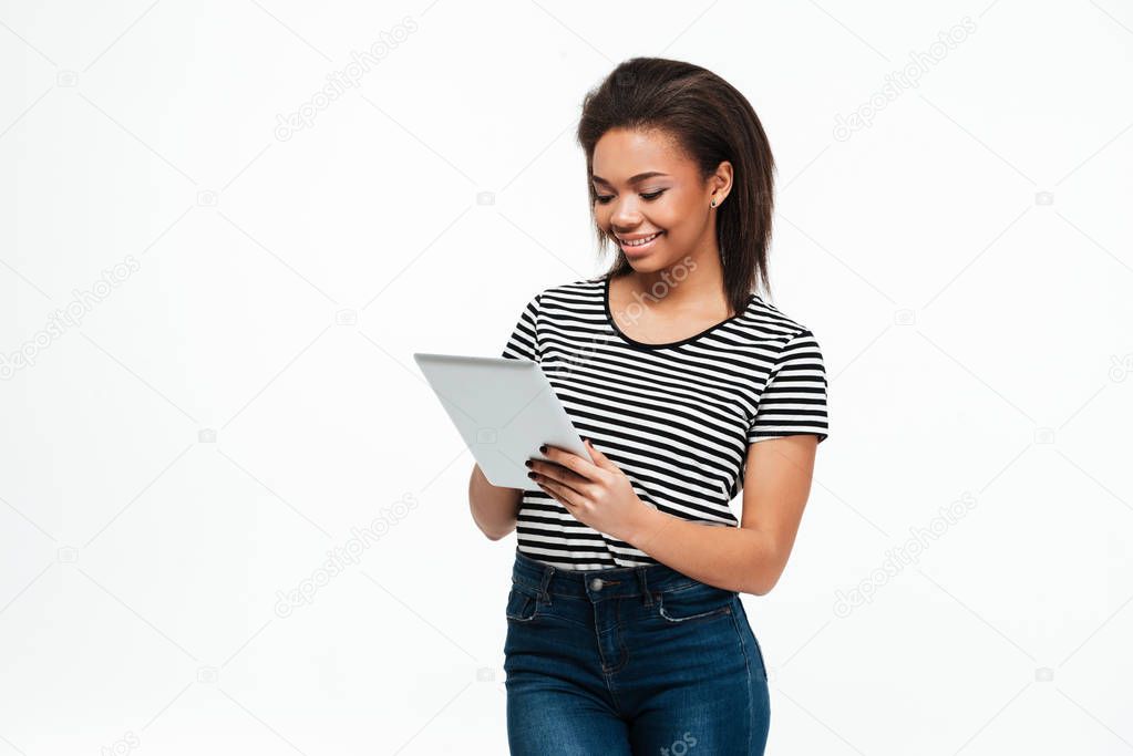Cheerful young african woman using tablet computer.