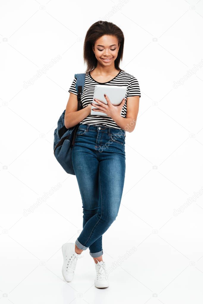 Happy pretty teenage girl wearing backpack and using pc tablet