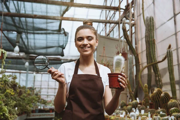 温室植物の近くに立っている笑顔の若い女性 — ストック写真