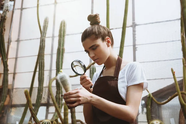 Jeune femme sérieuse debout dans une serre près des plantes — Photo