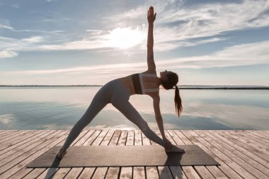 Spor Bayan kumsalda ayakta yapmak yoga egzersizleri.