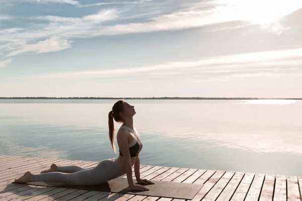 Erstaunliche junge Sportlerin am Strand machen Yoga-Übungen. — Stockfoto