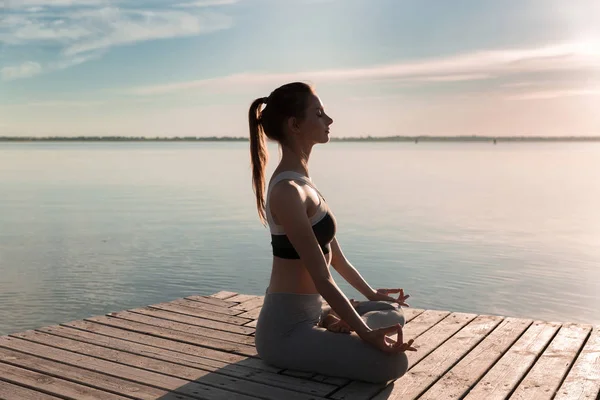 Sport van de jonge dame op het strand make meditatie oefeningen. — Stockfoto