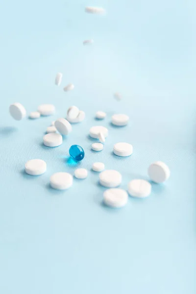 Comprimidos blancos caídos con una cápsula azul aislada — Foto de Stock