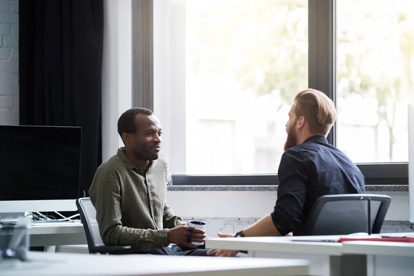 To unge mannlige kolleger som snakker med hverandre – stockfoto