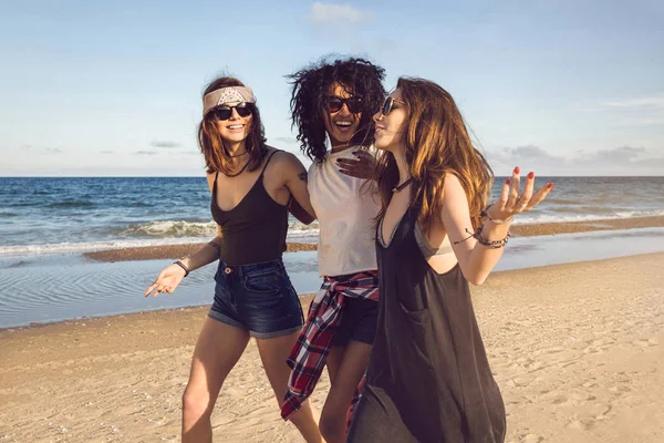 Trois amis marchant sur la plage et riant — Photo