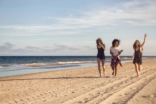 Groupe de trois belles jeunes femmes marchant sur la plage — Photo