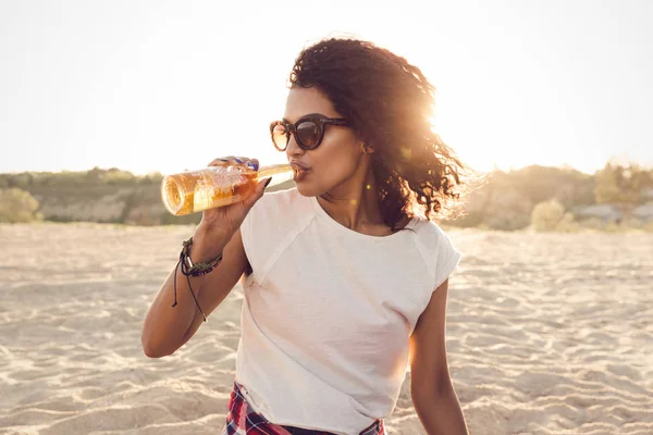 Joven chica africana bonita en gafas de sol bebiendo cerveza — Foto de Stock